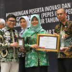 Kepala Dinas Perkebunan Kaltim, Ahmad Muzakkir menerima penghargaan yang diserahkan Staf Ahli Gubernur Bidang Polhukam, Ririn Sari Dewi (dok. Ist)